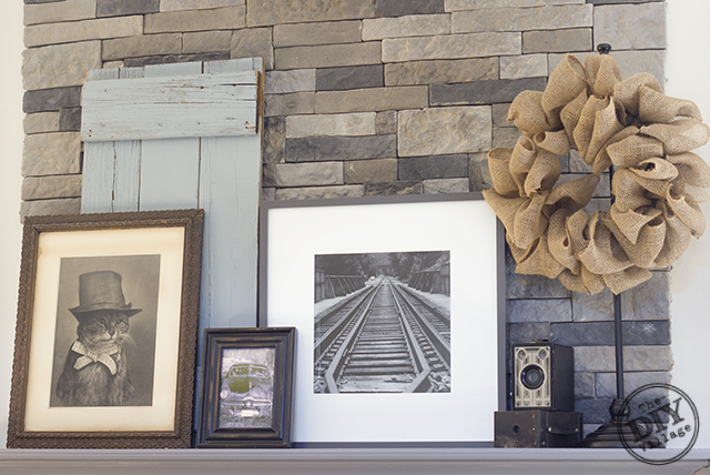 DIY stack stone fireplace makeover with Dover Gray Mantel. Great mix of rustic modern decor. Love the antique cameras and photographs