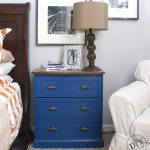 IKEA RAST Makeover blue dresser with hardwood top, glass lamp, and wall photos