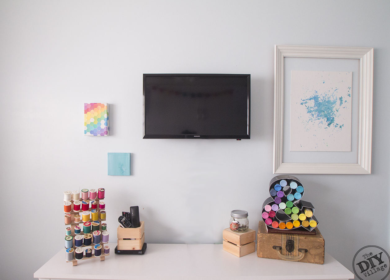 wall with art, tv, colorful thread, craft paints, craft room